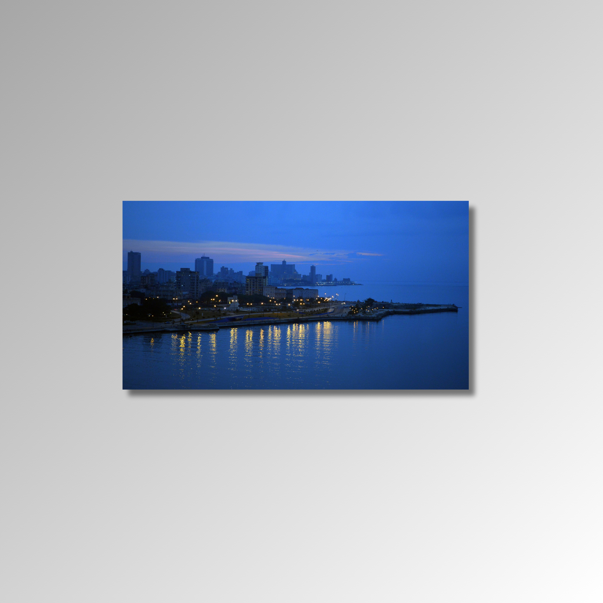 Cityscape at night with buildings and lights reflected in water on a gray background